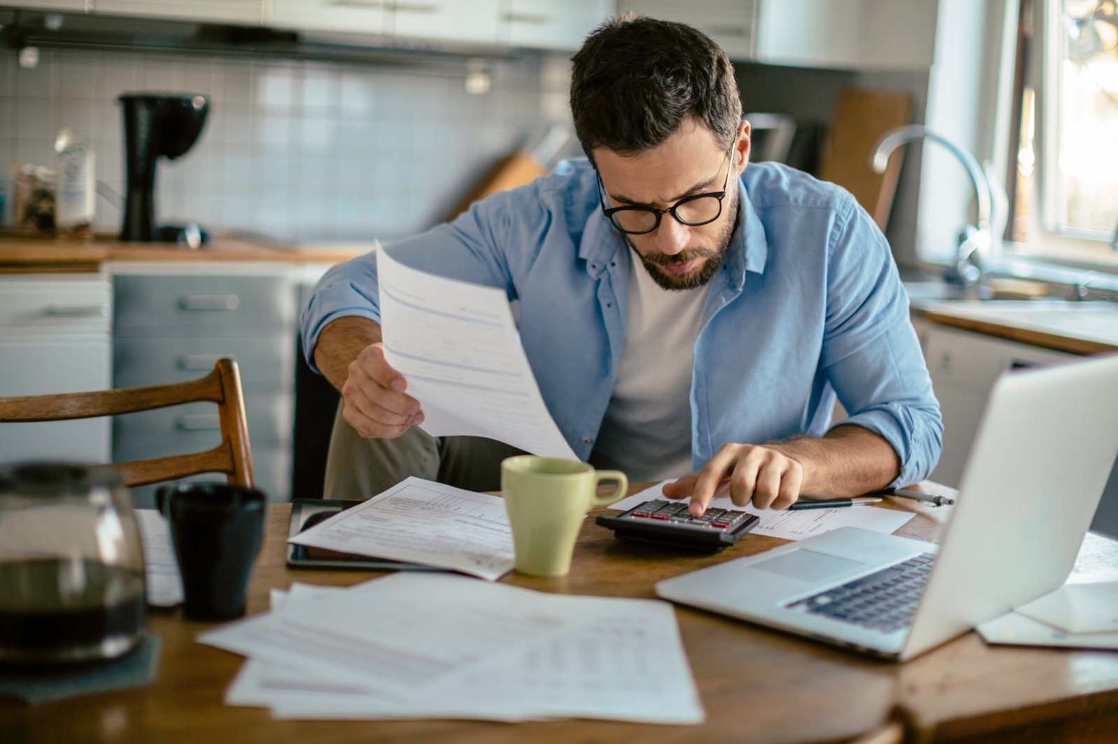 A man reviewing his finances at the kitchen table after a change in circumstances