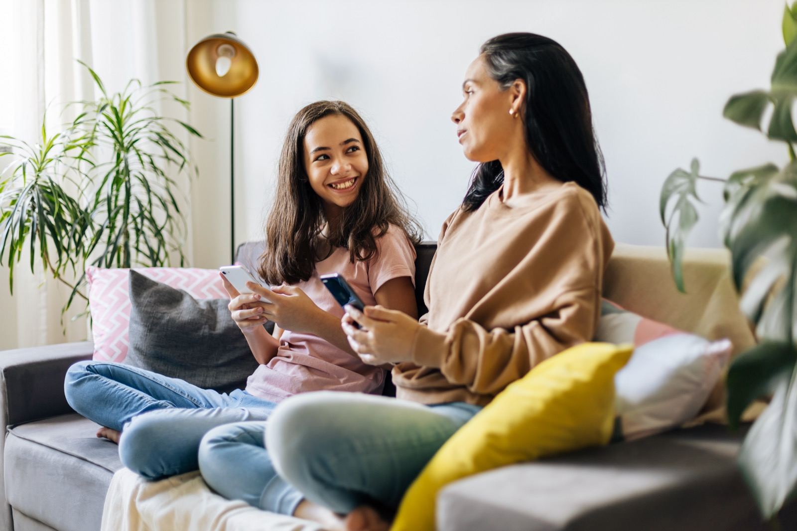 A mother and her teenage daughter talking together on the couch at home