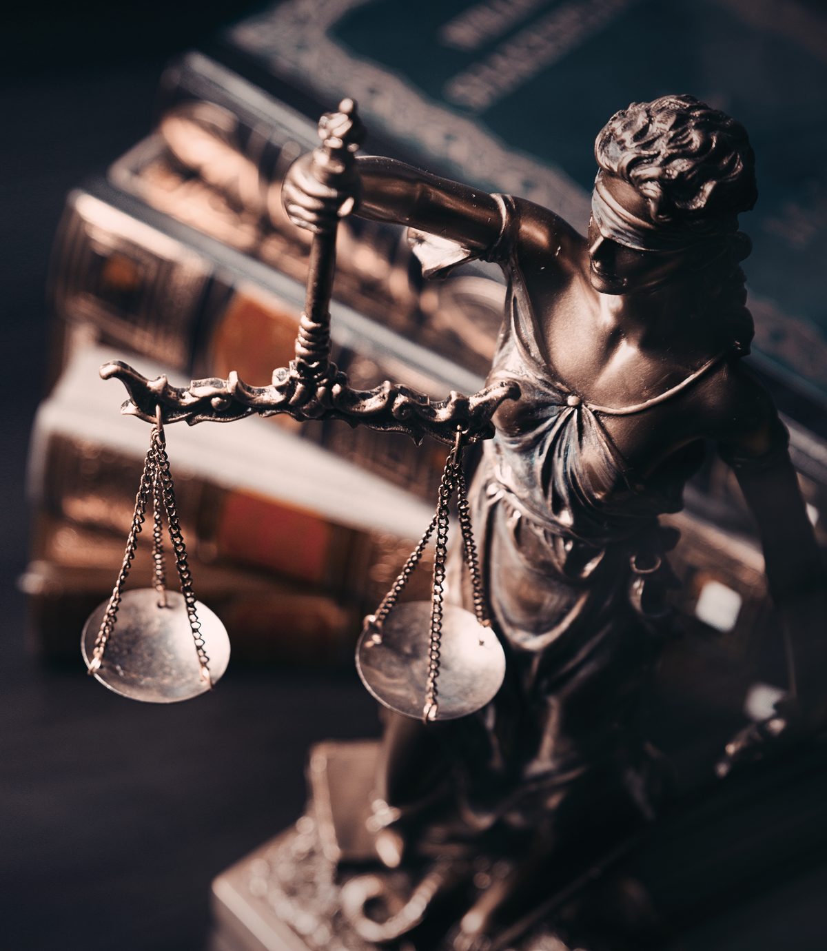 A bronze statue of Lady Justice in front of law books