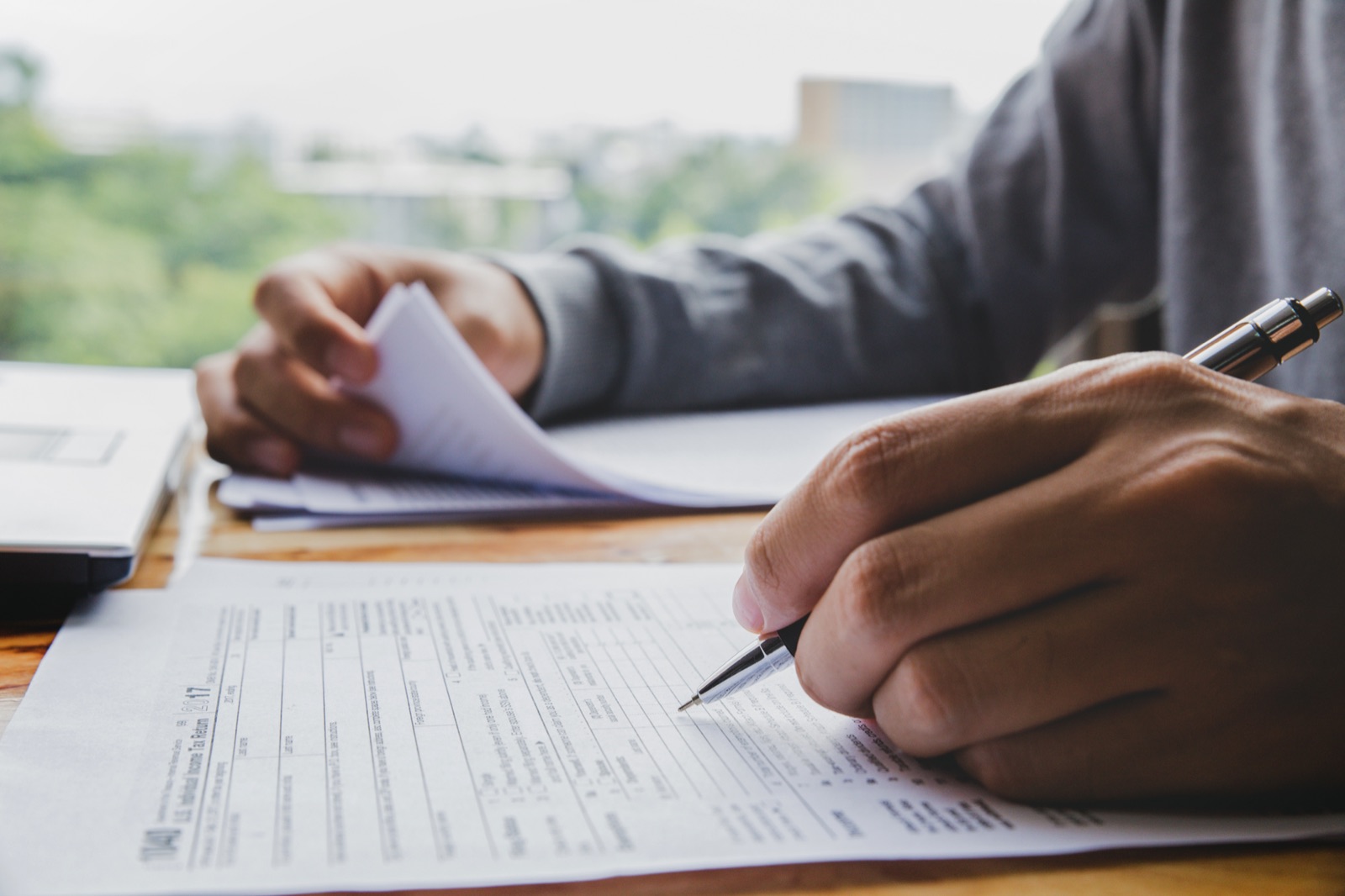 A person filling out a federal income tax return by hand