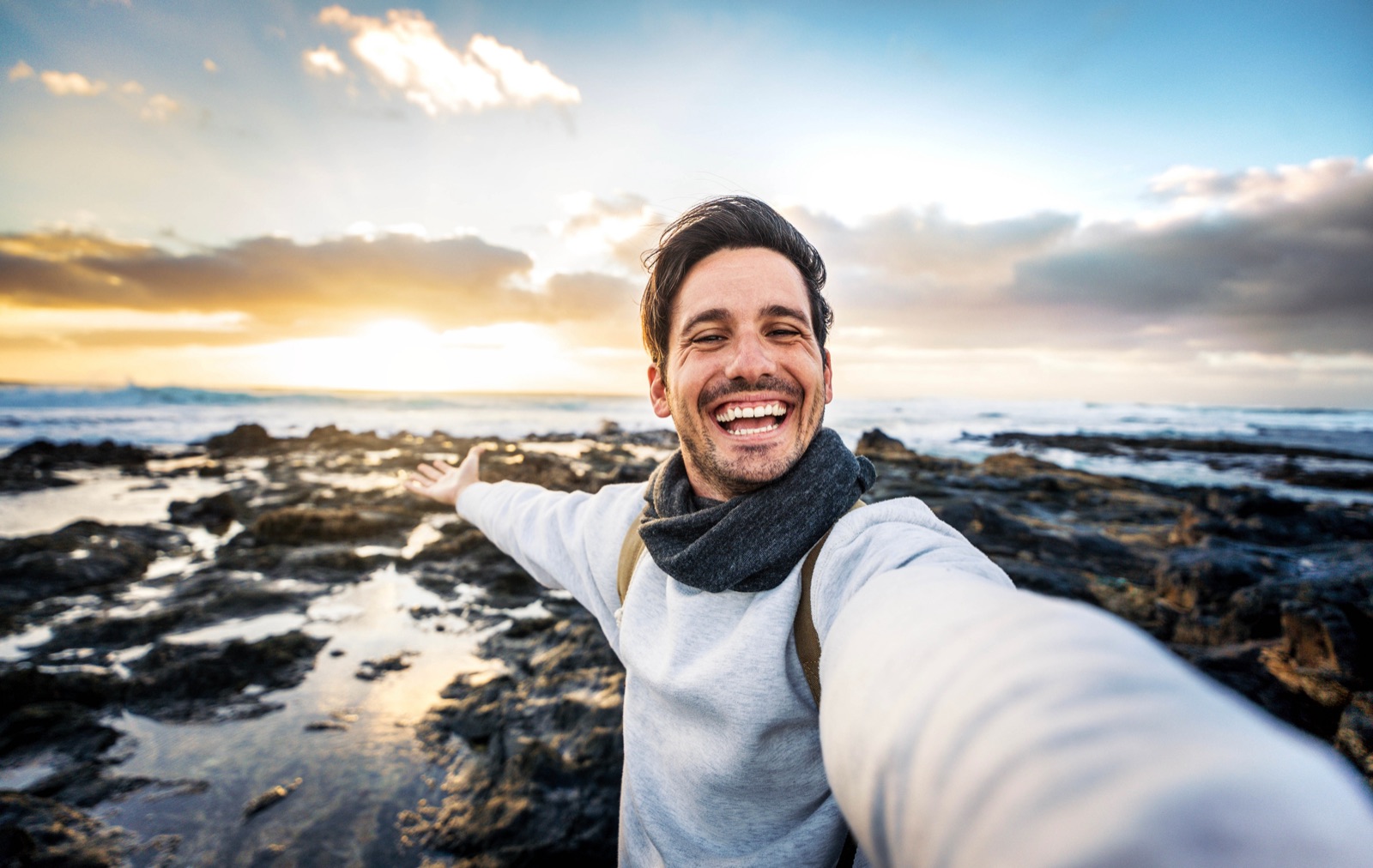 A man smiling at the shore at sunrise